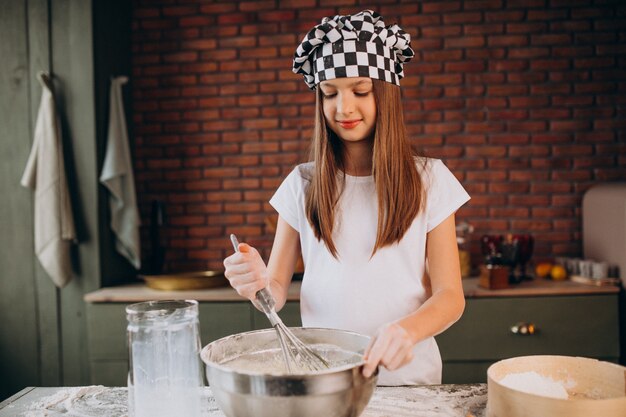 Junges kleines Mädchen, das Gebäck an der Küche zum Frühstück backt