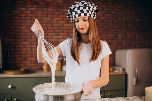 Junges kleines Mädchen, das Gebäck an der Küche zum Frühstück backt