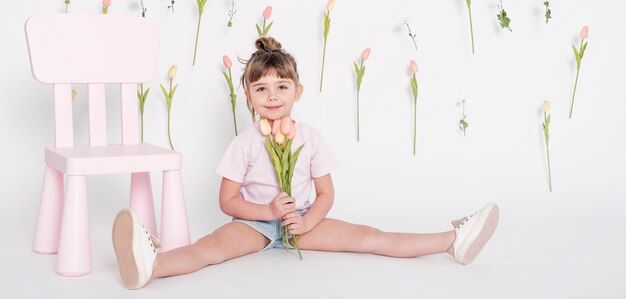 Junges kleines Mädchen, das Tulpen hält