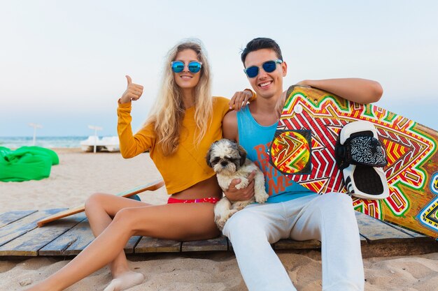 Junges lächelndes Paar, das Spaß am Strand mit Drachensurfbrett in den Sommerferien hat