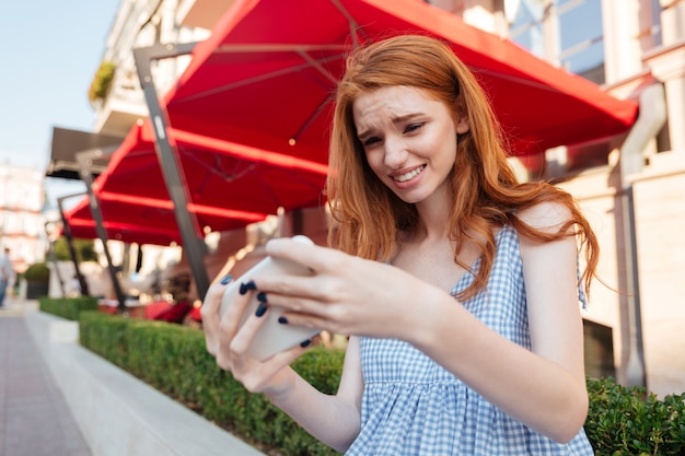 Junges lässiges Mädchen, das Spiele auf Handy spielt