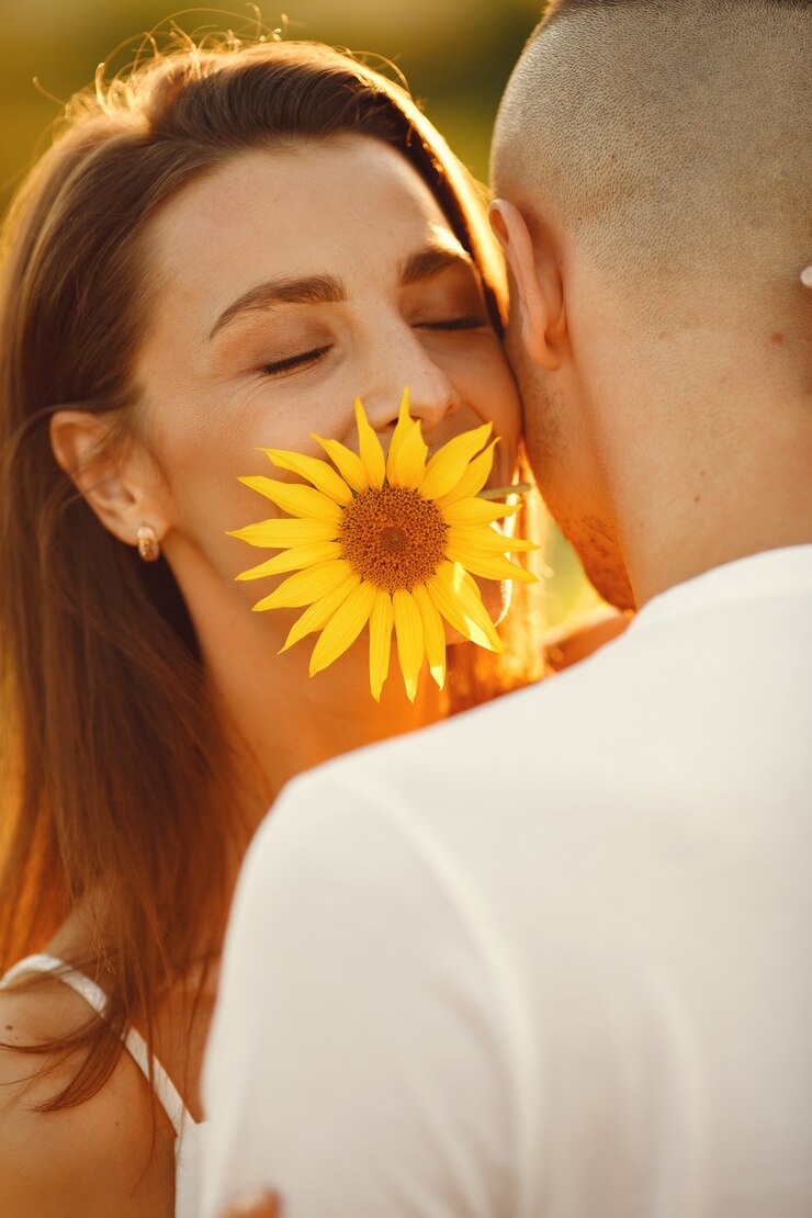 Junges liebendes Paar küsst in einem Sonnenblumenfeld. Porträt des Paares, das im Sommer im Feld aufwirft.