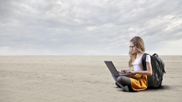 Kostenloses Foto junges mädchen arbeitet mit einem pc in der wüste