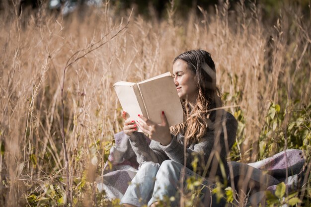 junges Mädchen auf einem Feld, das ein Buch liest