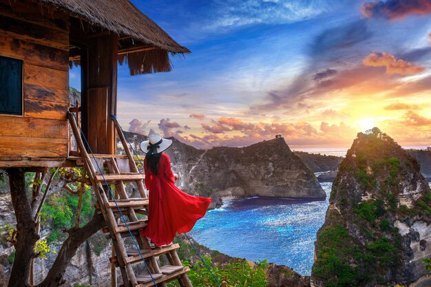 Junges Mädchen auf Stufen des Hauses auf Baum bei Sonnenaufgang in Nusa Penida Insel, Bali in Indonesien