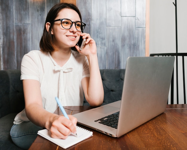 Junges mädchen, das am telefon im büro spricht