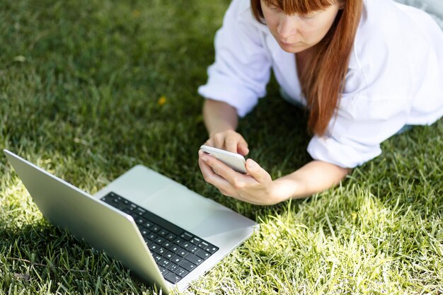 Junges Mädchen, das an einem Computer im Park arbeitet