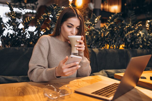 Junges Mädchen, das an einem Computer in einem Café arbeitet