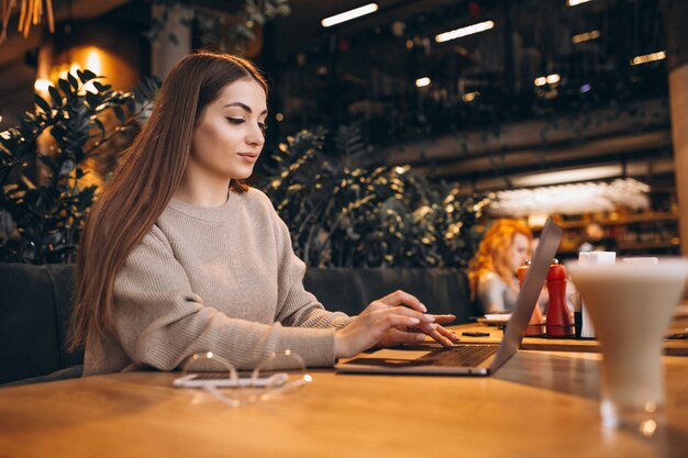 Junges Mädchen, das an einem Computer in einem Café arbeitet