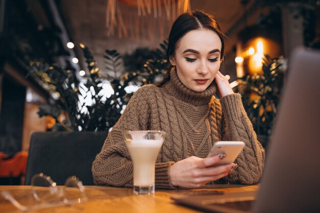 Junges Mädchen, das an einem Computer in einem Café arbeitet