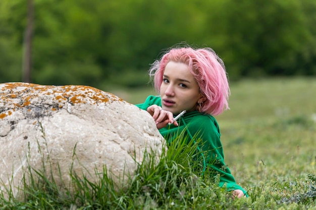 Junges Mädchen, das auf dem Gras liegt und raucht