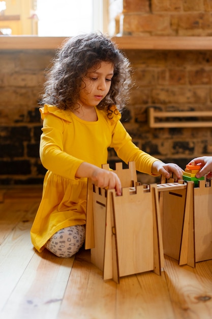 Junges Mädchen, das drinnen mit Öko-Spielzeug spielt