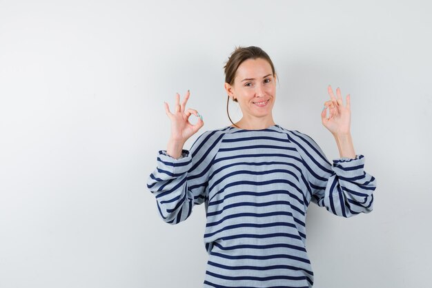 Junges Mädchen, das ein OK-Handzeichen auf weißem Hintergrund hält