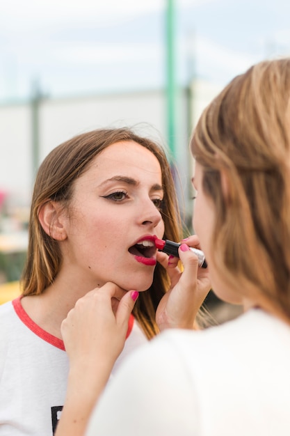 Junges Mädchen, das ihrem Freund mit dem Lippenstift hilft