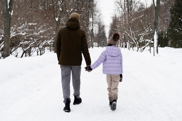 Junges Mädchen, das im Winter mit ihrem Vater spazieren geht