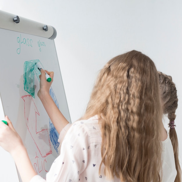 Junges Mädchen, das Recyclingschild auf Whiteboard zeichnet