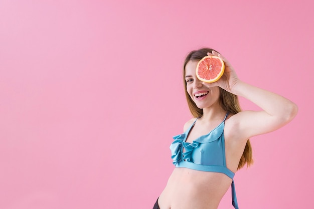 Kostenloses Foto junges mädchen im bikini mit grapefruit