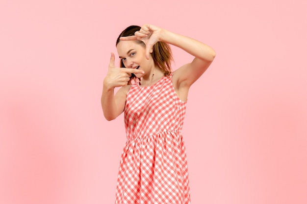 junges Mädchen im niedlichen rosa Kleid im Bild, das Pose auf rosa nimmt