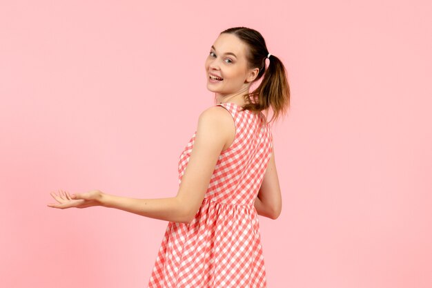 junges Mädchen im niedlichen rosa Kleid mit aufgeregtem Ausdruck auf rosa