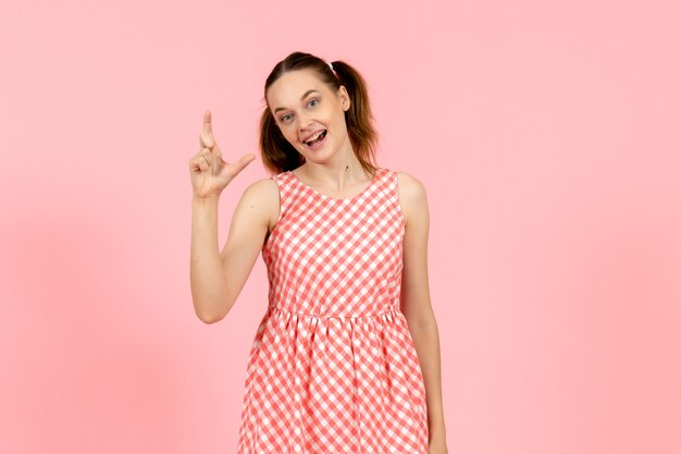 junges Mädchen im niedlichen rosa Kleid mit aufgeregtem Ausdruck auf rosa