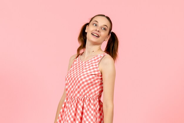 junges Mädchen im niedlichen rosa Kleid mit lächelndem Gesicht auf rosa