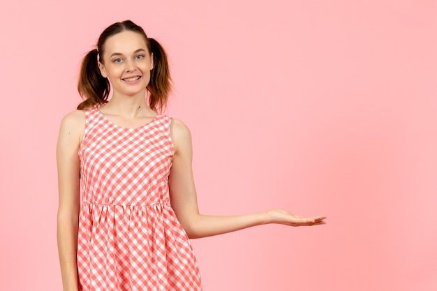 junges Mädchen im niedlichen rosa Kleid mit lächelndem Gesicht auf rosa