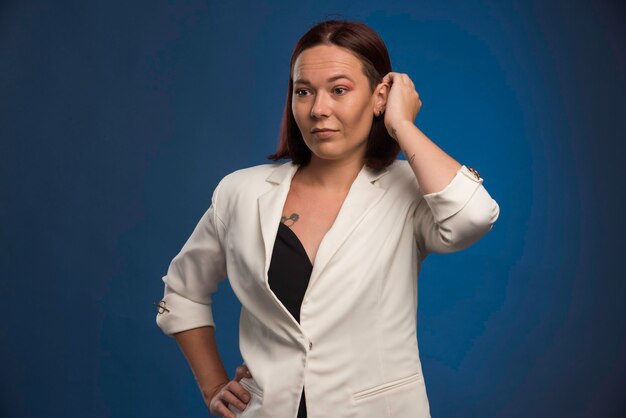 Junges Mädchen im weißen Blazer posiert.