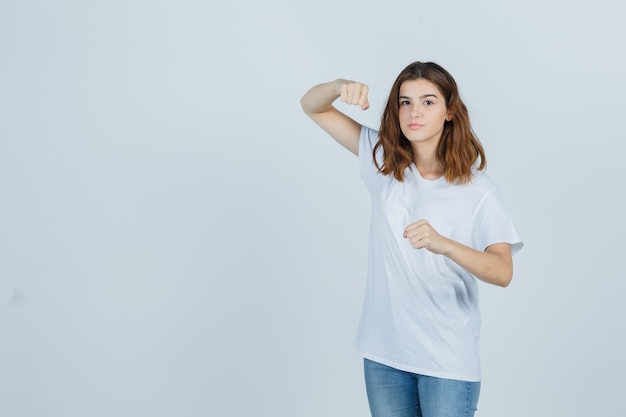 Kostenloses Foto junges mädchen im weißen t-shirt, jeans, die in der kampfhaltung stehen und stark schauen, vorderansicht.