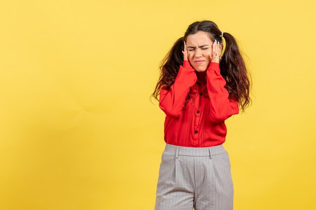 junges Mädchen in der roten Bluse, die unter Kopfschmerzen auf Gelb leidet