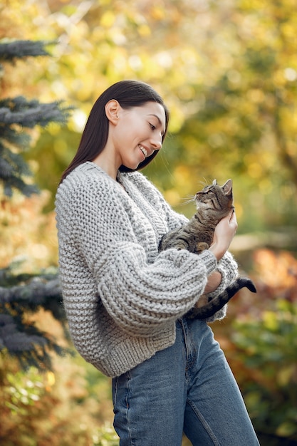 Junges Mädchen in einem grauen Pullover, der draußen mit einer Katze aufwirft