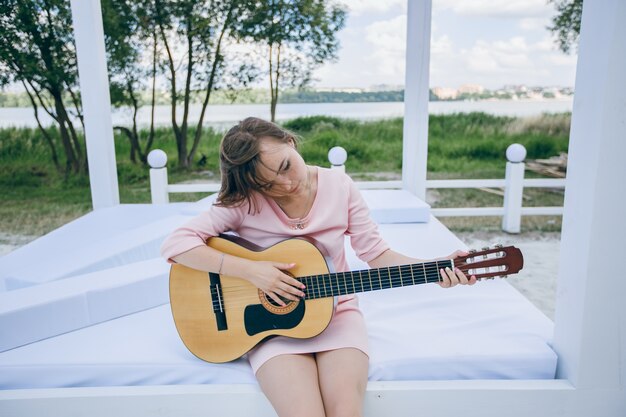 Junges Mädchen in einem rosa Kleid spielt eine Gitarre