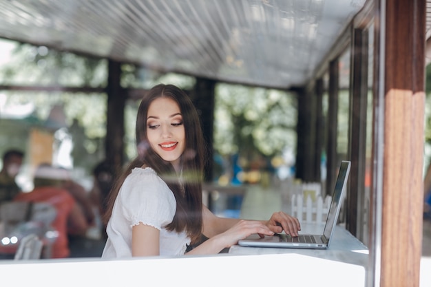 Junges Mädchen in einer Cafeteria sitzt mit einem Laptop