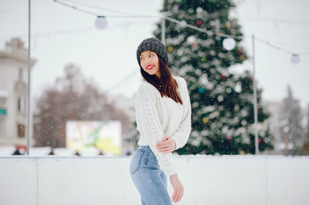 Junges Mädchen in einer weißen Strickjacke, die in einem Winterpark steht