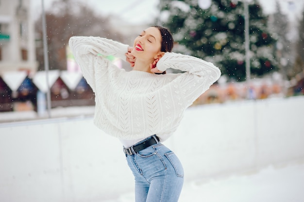 Kostenloses Foto junges mädchen in einer weißen strickjacke, die in einem winterpark steht