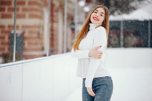 Junges Mädchen in einer weißen Strickjacke, die in einem Winterpark steht