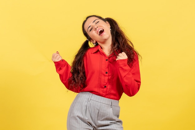 junges Mädchen in roter Bluse in tanzender Pose auf Gelb