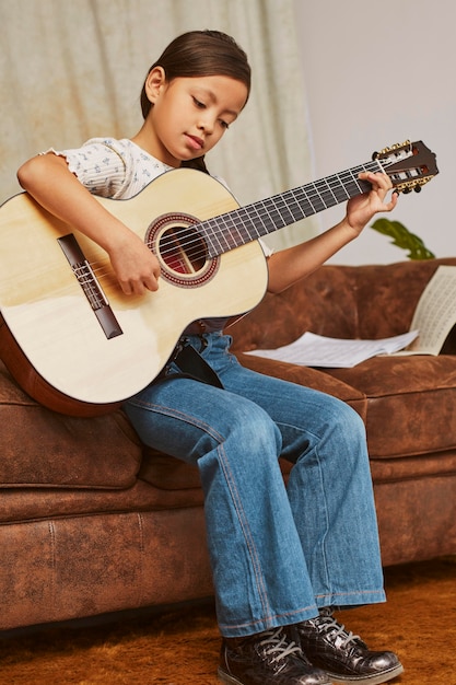 Junges Mädchen lernt, wie man zu Hause Gitarre spielt