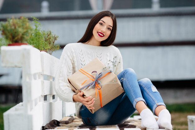 Junges Mädchen mit einem Geschenk auf dem Schoß lächelnd