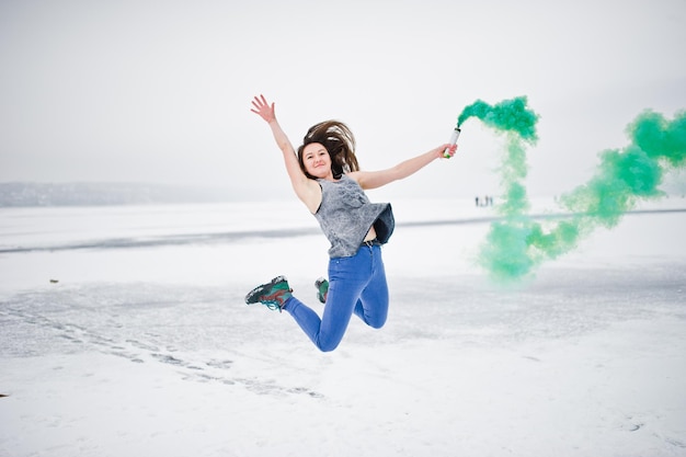 Kostenloses Foto junges mädchen mit grüner rauchbombe in der hand am wintertag