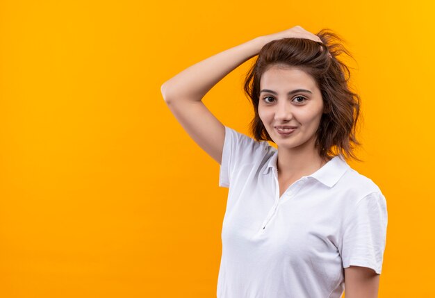 Junges Mädchen mit kurzen Haaren, die weißes Poloshirt tragen Kamera mit Lächeln auf Gesicht betrachten