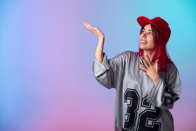 Junges Mädchen mit rosa Haaren in Straßenartoutfits, die etwas zeigen.