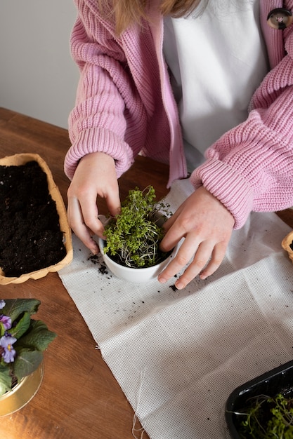 Junges Mädchen mit viel Grün in Upcycled-Topf gepflanzt