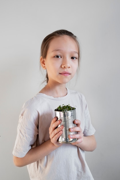 Junges Mädchen mit viel Grün in Upcycled-Topf gepflanzt