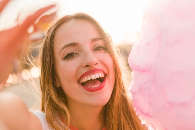 Junges Mädchen mit Zuckerwatte im Vergnügungspark