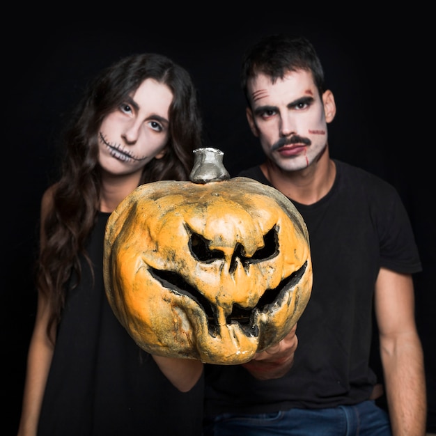 Junges Mädchen und Kerl, die gruselige Jack-O-Laterne halten