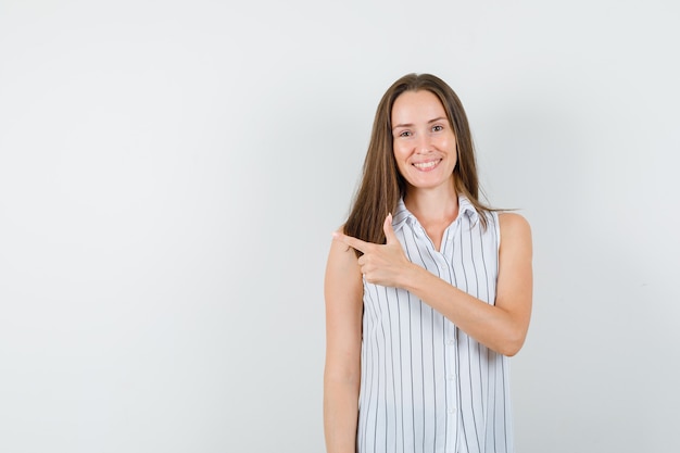 Junges Mädchen zeigt zur Seite im T-Shirt und schaut optimistisch, Vorderansicht.