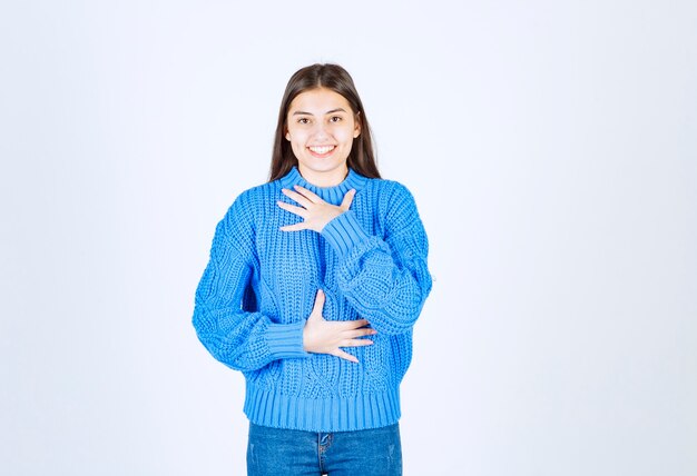 junges Mädchenmodell im blauen Pullover, der auf weiß-grau steht und posiert.