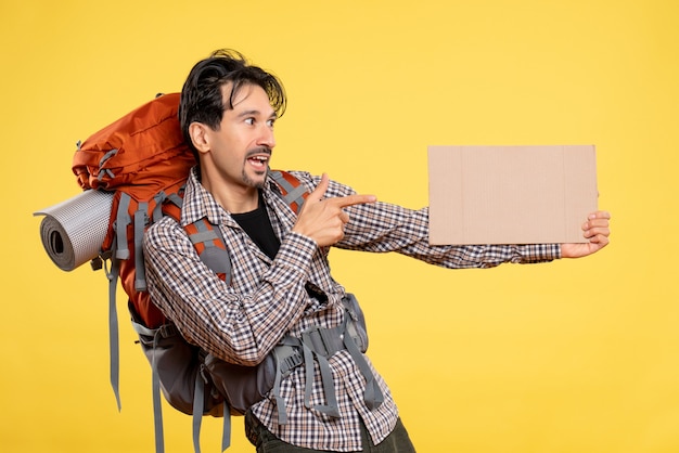 Junges Männchen der Vorderansicht, das mit dem Rucksack auf gelb wandert