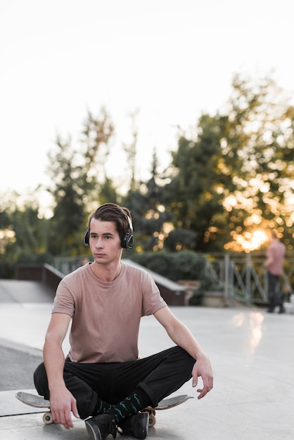 Kostenloses Foto junges männliches baumuster, das auf skateboard sitzt