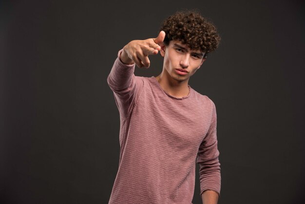 Junges Modell mit den lockigen Haaren, die als Gangster posieren.